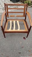 Front view of teak armchair frame showing slatted support strips and curved armrests, no upholstery