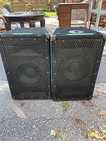 Pair of black Woods System event speakers front view showing metal grille and wear.