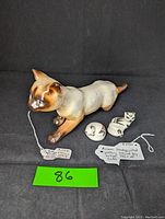 Vintage E & R Crown Austria stalking Siamese cat figurine and pair of Acoma hand painted pottery cats on black background with tags