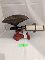 Front angle of antique Fairbanks mercantile scale showing red metal base, brass pan, and rate card attached to measurement bar.