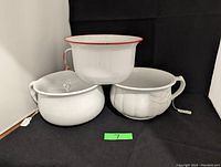 All three chamber pots together: two white ironstone pots and one white enamel metal pot with red rim