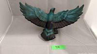 Front view of large blue and black ceramic bird figurine with its wings spread in flight pose.