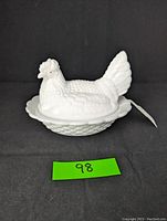 Side view of white milk glass hen on nest base with textured details