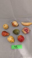Top view of all eight alabaster fruit pieces arranged on surface