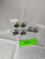 Four cufflinks arranged in two pairs. One pair is Guy Vidal pewter brutalist style and the other pair carved stone face cufflinks.