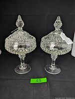 Pair of vintage Indiana Glass diamond point lidded compotes shown from front on black background.