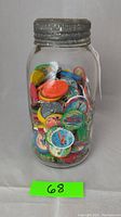 Clear antique mason jar filled with colorful vintage airplane coins under metal lid