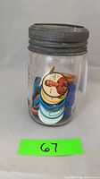 Front view of antique Crown jar filled with colorful Salada hockey coins, showing player image on a coin