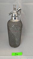 Front view of vintage Sparklets seltzer bottle showing diamond glass pattern and metal dispenser top.