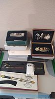 Collection of pocket cutters and miniature decorative weapons displayed in boxes on a table.