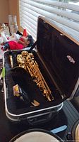 Alto saxophone body, neck, mouthpiece, and reed box inside open hard case
