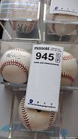 Three baseballs in clear display cubes on a wall-mounted rack, front and top views. Two baseballs signed in black ink, one is not signed. One signature faded.