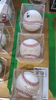 Three signed baseballs in clear plastic display cases shown from above, showing overall lot contents.