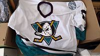 Photo of white Anaheim Mighty Ducks hockey jersey with teal and black colors and team logo on chest