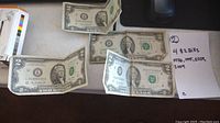 Four U.S. two dollar bills laid out on a flat surface with a note listing their years: 1976, 1995, 2009, 2009.