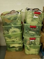 8 green plastic bins stacked, each containing tightly packed novelty belts mostly in plastic wrapping and loose form.