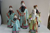 Full view of all five porcelain wise sage figurines showing different sizes and colors of traditional robes and features