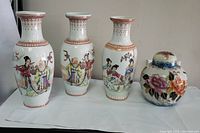 Front view of three Chinese-style porcelain vases showing life scenes hand-painted with traditional figures and one rounded ginger jar with floral motifs and gold accents.