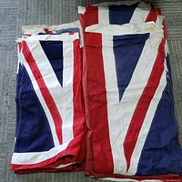 Folded British sailing flags showing the red, white, and blue Union Jack pattern on fabric.