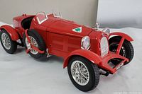 Three-quarter front view of red Alfa Romeo 2300 Monza model showing front grille, headlights, and side mounted spare tire