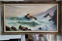 Front view of large horizontal oil painting of sea with waves and rocks in detailed frame