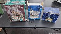 Photo of the three Christmas village houses still in their original boxes on a table.