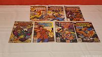 Seven comic books laid flat, showing front covers with Human Torch and Fantastic Four titles
