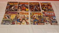 Eight vintage Marvel comic books arranged in two rows: two Iron Man, two Avengers, and four Thor comics. Covers display artwork and logos typical of vintage Marvel issues.