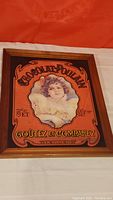 Full view of the Chocolat Poulain advertising mirror with a wooden frame showing the vintage printed image of a young woman and brand text.