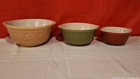 Full set of three graduated ceramic mixing bowls side by side, showing size and color differences.