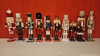 Overall view of 10 assorted nutcracker figurines against red backdrop