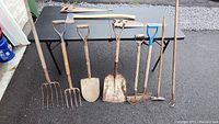 Full view of 7 garden tools on asphalt and black table background
