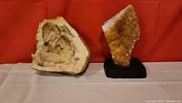 Pair of geological geodes displayed against red background, showing one larger and one smaller mounted geode.