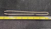 Full chain necklace measuring around 18 inches with a box link design shown alongside a measuring tape.