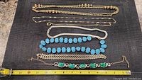 Full lot showing all necklaces and bracelet alongside measuring tape showing lengths