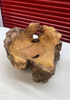 Overview of carved burl wood bowl on white surface against red background showing overall shape and grain