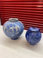 Two blue crystalline porcelain vases side by side on a surface, showing varying sizes and shapes.