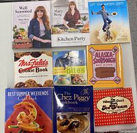 Photo of nine cookbooks arranged on a white surface, showing front covers of each cookbook clearly. Titles and authors are visible.