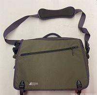 Front view of green canvas briefcase with zippered pocket and adjustable shoulder strap