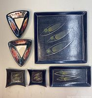 Six porcelain plates and dishes arranged on a white surface showing the color and fish motifs of the lot