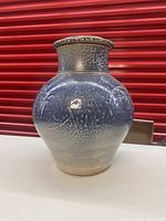 Full frontal view of tall salt-glazed pottery lidded jar showing blue-grey glaze and embossed circular patterns.