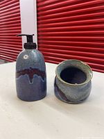 Full view of the blue and green pottery soap dispenser with a black pump and matching pottery dish, showing overall shape and glaze.