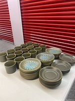Photo showing all cups, saucers, and plates arranged on a table with red background.