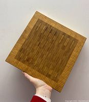 Top view showing the inlaid teak and walnut wood strips pattern and maple trim on the chopping board.