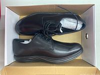 Photo of pair of black MBT shoes in open box showing side and top view.