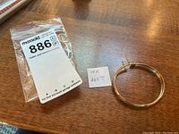 Top-down view of bracelet lying flat next to note reading “10K 665.00” and MaxSold bag label