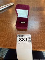 Ring in red velvet presentation box with lot tag visible