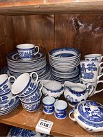 Overview of top shelf with stacks of plates, bowls, cups, saucers, creamers and sugar bowl