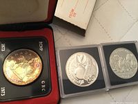 Photo showing all three coins: the 1973 RCMP coin in presentation case, 1996 Manitoba coin, and Canadian Parliament coin.