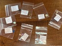 Seven small ziplock bags containing opals, opal doublets, mineral specimens, and a gold ring with a synthetic stone and broken claw setting.